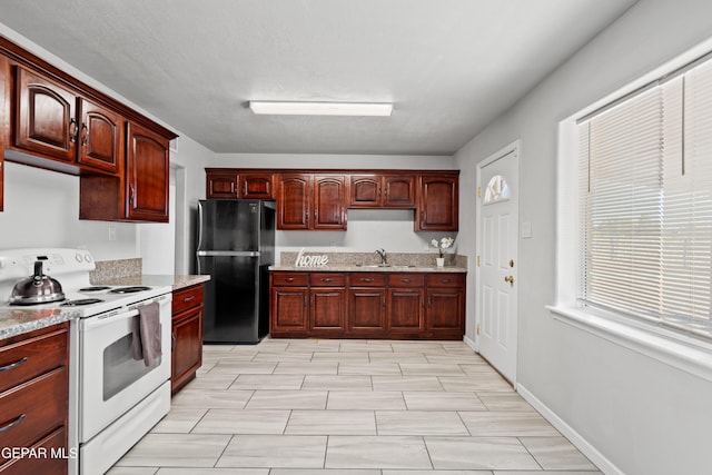 kitchen with black fridge, white range with electric cooktop, and sink