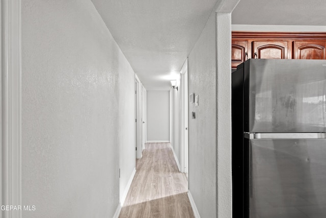 corridor featuring a textured ceiling and light wood-type flooring