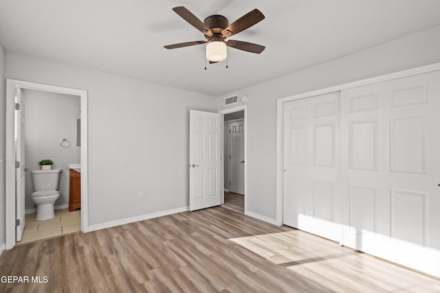 unfurnished bedroom with ceiling fan, light hardwood / wood-style floors, ensuite bathroom, and a closet