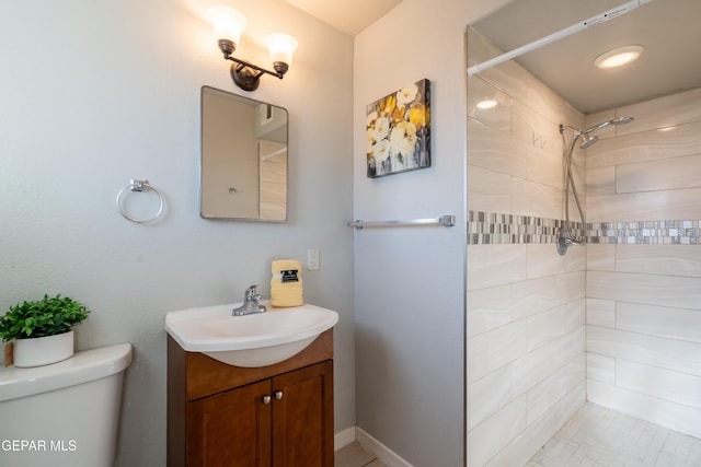 bathroom featuring toilet, tiled shower, and vanity