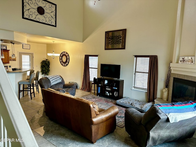 living room featuring a towering ceiling, a notable chandelier, and a fireplace