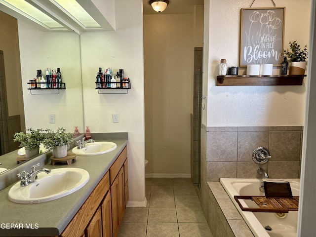 bathroom with a relaxing tiled tub, vanity, and tile patterned flooring