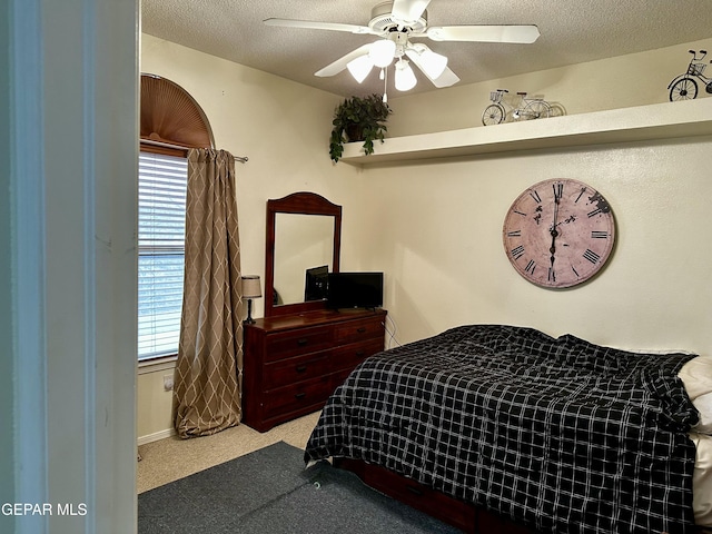 carpeted bedroom featuring ceiling fan and a textured ceiling