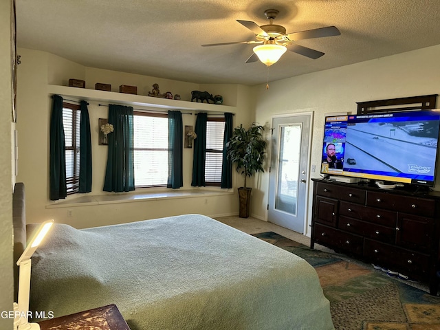 carpeted bedroom featuring ceiling fan and a textured ceiling