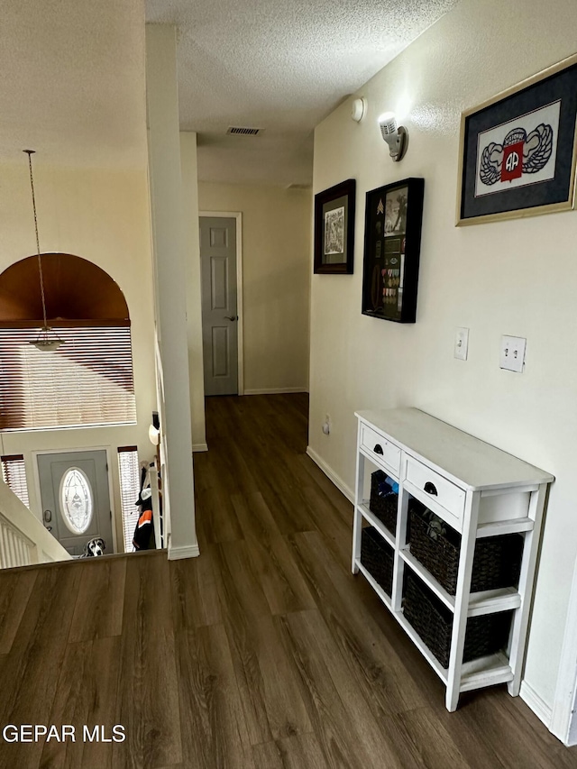 corridor with dark wood-type flooring and a textured ceiling