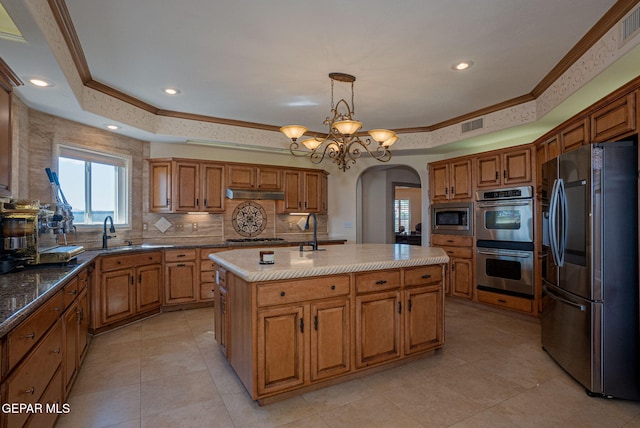 kitchen featuring stainless steel appliances, a kitchen island with sink, crown molding, sink, and a notable chandelier