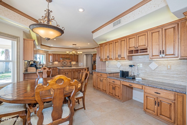 kitchen featuring backsplash, a raised ceiling, dark stone countertops, and pendant lighting