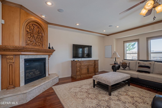 living room featuring ceiling fan, wood-type flooring, ornamental molding, and a premium fireplace