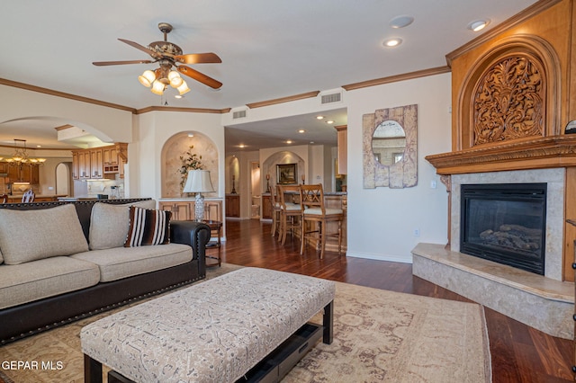 living room with ceiling fan with notable chandelier, dark hardwood / wood-style floors, a premium fireplace, and ornamental molding