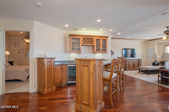 kitchen featuring ceiling fan, a center island, wine cooler, dark hardwood / wood-style floors, and a breakfast bar