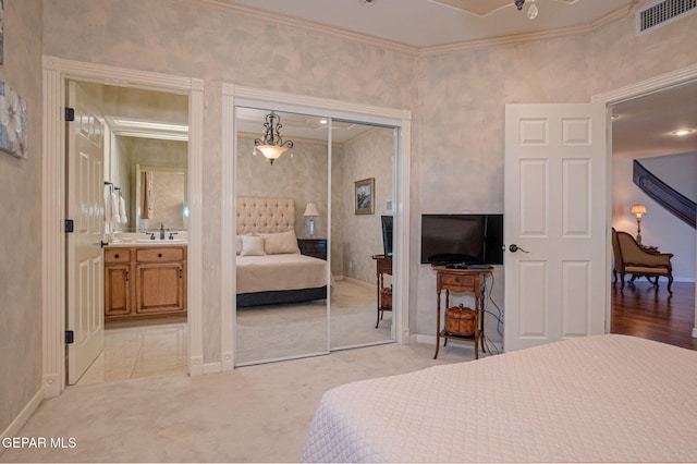 carpeted bedroom with crown molding, a closet, and sink