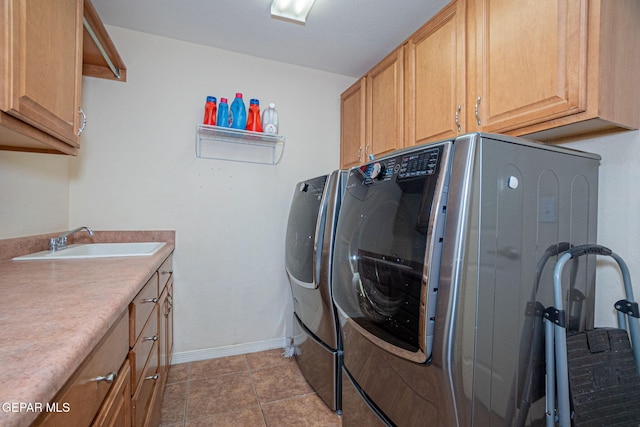 clothes washing area featuring tile patterned floors, washing machine and dryer, sink, and cabinets