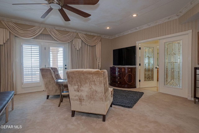 living area featuring light carpet, ceiling fan, and ornamental molding