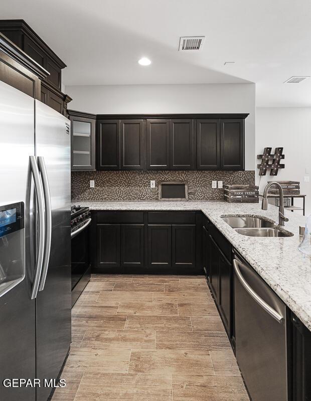 kitchen featuring light stone counters, sink, stainless steel appliances, and tasteful backsplash