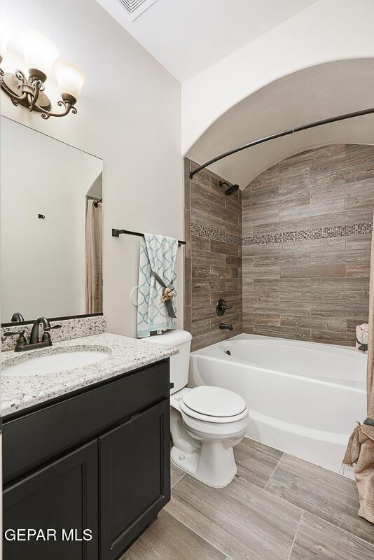 full bathroom with vanity, tiled shower / bath combo, and toilet