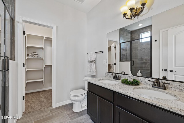 bathroom with a notable chandelier, vanity, toilet, and walk in shower