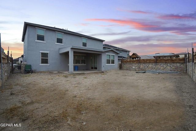 back house at dusk featuring a patio