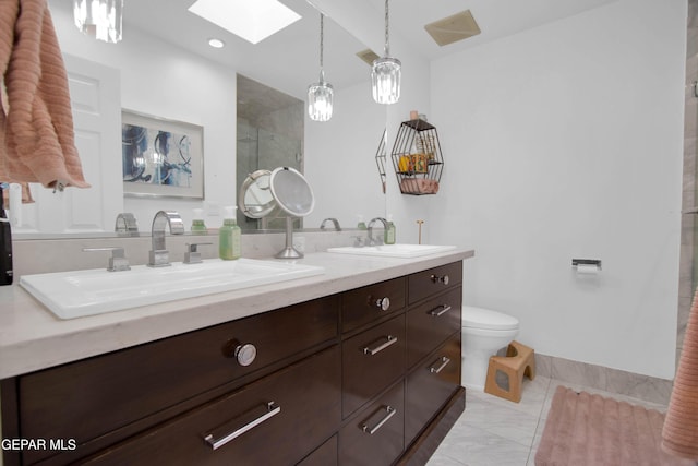 bathroom featuring a tile shower, vanity, a skylight, and toilet