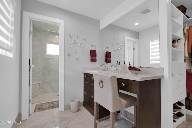 bathroom featuring tiled shower and vanity