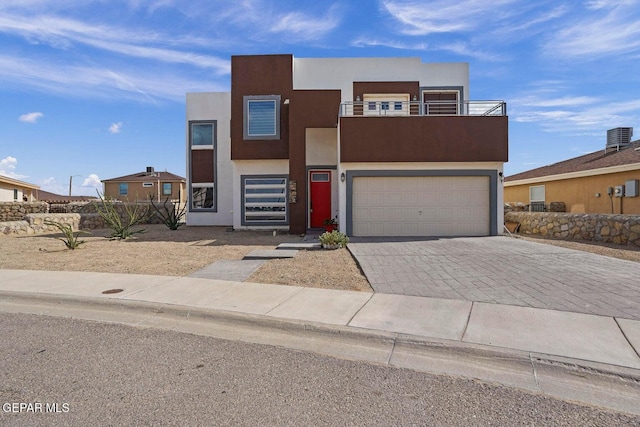 view of front facade featuring a balcony, a garage, and cooling unit