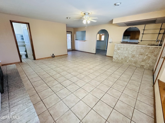 unfurnished living room with ceiling fan, sink, and light tile patterned floors