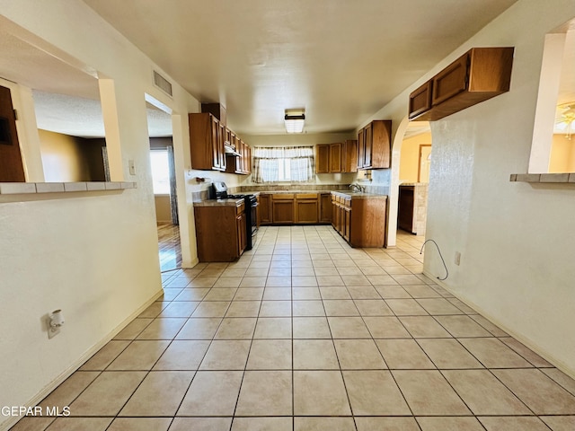 kitchen featuring electric range, sink, and light tile patterned floors