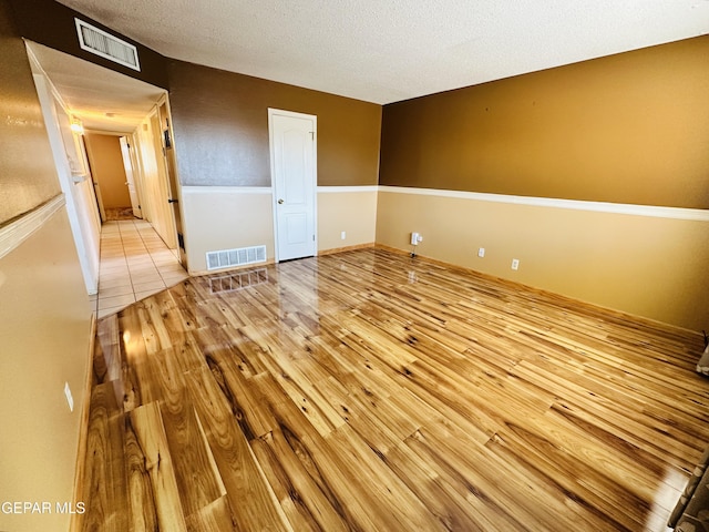 unfurnished room with light hardwood / wood-style floors and a textured ceiling