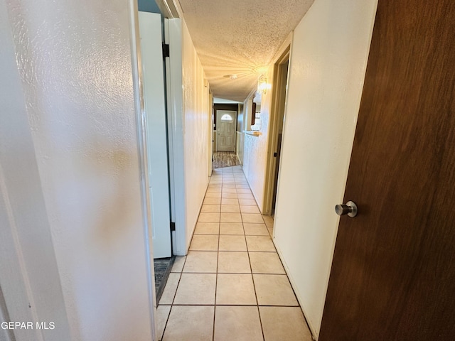 hallway featuring light tile patterned floors and a textured ceiling