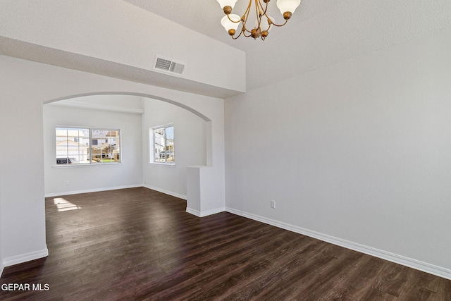 empty room featuring a textured ceiling, dark hardwood / wood-style floors, and an inviting chandelier