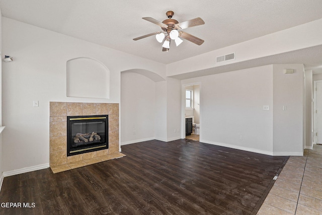 unfurnished living room featuring ceiling fan, hardwood / wood-style flooring, and a tile fireplace