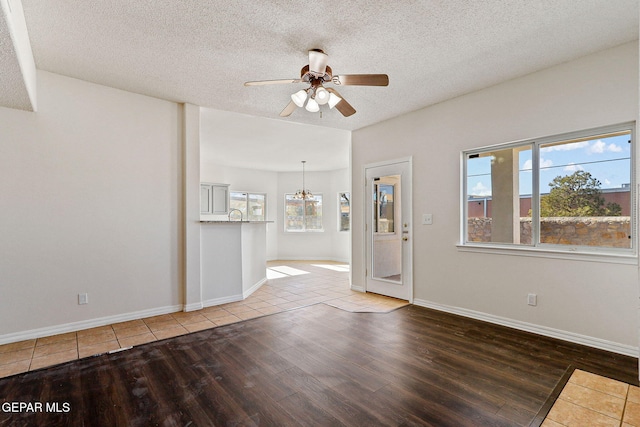 unfurnished room featuring ceiling fan with notable chandelier, wood-type flooring, and a textured ceiling