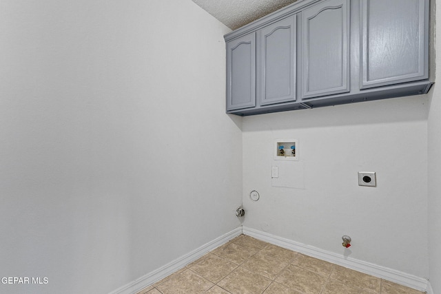 washroom with hookup for an electric dryer, hookup for a gas dryer, a textured ceiling, washer hookup, and cabinets