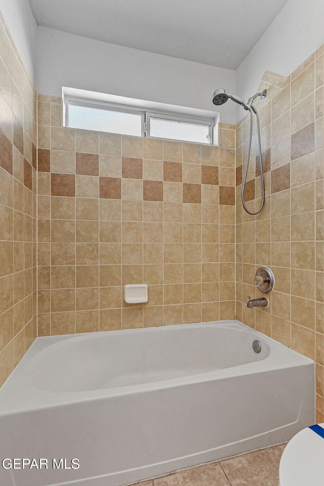 bathroom featuring toilet, tiled shower / bath combo, and tile patterned flooring