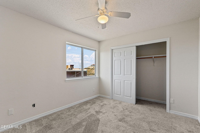 unfurnished bedroom featuring a textured ceiling, ceiling fan, a closet, and light colored carpet