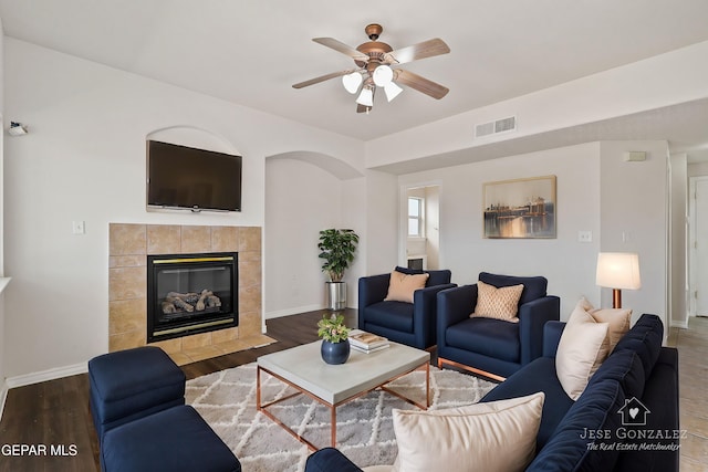 living room with ceiling fan, hardwood / wood-style floors, and a tile fireplace