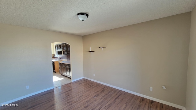 empty room with a textured ceiling and light hardwood / wood-style flooring