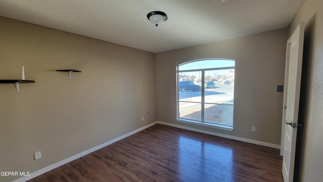 unfurnished room with dark hardwood / wood-style flooring and a textured ceiling