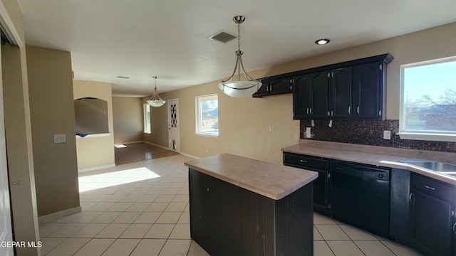 kitchen featuring pendant lighting, light tile patterned flooring, black dishwasher, tasteful backsplash, and a kitchen island