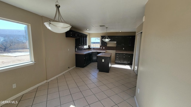 kitchen featuring backsplash, sink, pendant lighting, a center island, and light tile patterned flooring