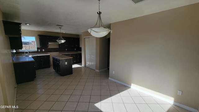 kitchen featuring sink, hanging light fixtures, light tile patterned floors, tasteful backsplash, and a kitchen island