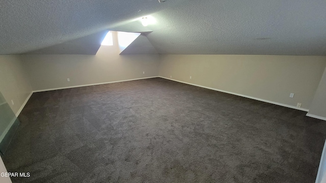 bonus room featuring a textured ceiling, dark carpet, and vaulted ceiling