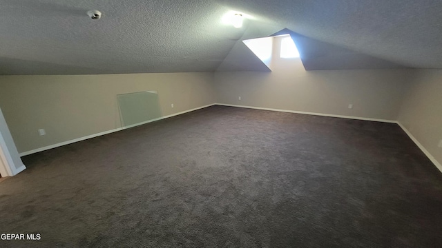 additional living space featuring lofted ceiling, dark carpet, and a textured ceiling