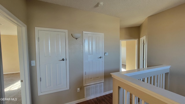 hallway with dark hardwood / wood-style floors and a textured ceiling