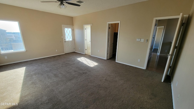 unfurnished bedroom featuring ensuite bathroom, a textured ceiling, ceiling fan, dark colored carpet, and a closet