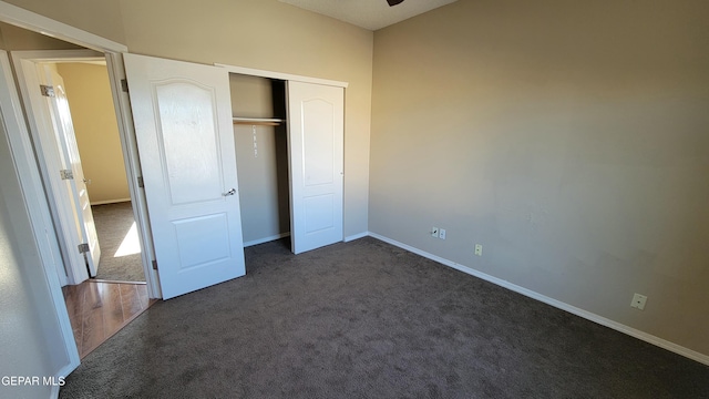 unfurnished bedroom featuring dark carpet and a closet