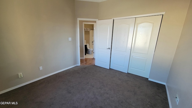 unfurnished bedroom featuring a closet and dark colored carpet