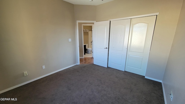 unfurnished bedroom featuring a closet and dark carpet