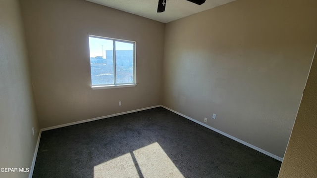 empty room featuring ceiling fan and dark carpet