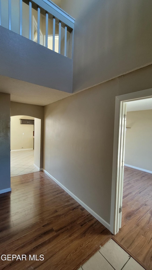 corridor featuring hardwood / wood-style floors and a towering ceiling