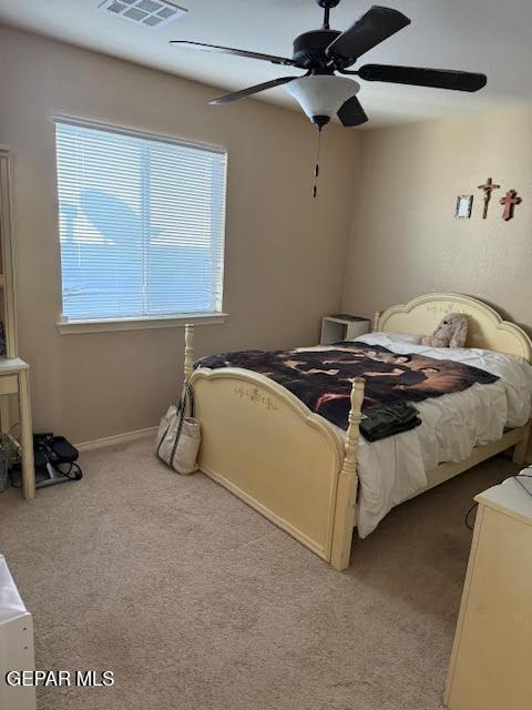 bedroom with light carpet, ceiling fan, visible vents, and baseboards